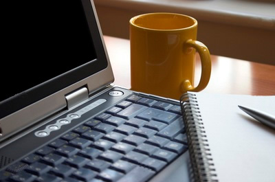 laptop, writing pad and a coffee mug